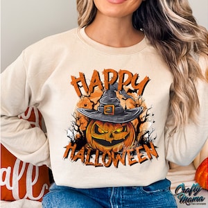 Peut inclure: Un sweat-shirt beige avec un imprim&eacute; graphique d'une citrouille portant un chapeau de sorci&egrave;re. Le texte "Happy Halloween" est imprim&eacute; sur le sweat-shirt.