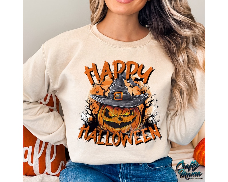 Peut inclure: Un sweat-shirt beige avec un imprim&eacute; graphique d'une citrouille portant un chapeau de sorci&egrave;re. Le texte "Happy Halloween" est imprim&eacute; sur le sweat-shirt.