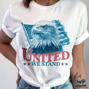 May include: White t-shirt featuring a blue and red American flag design and a bald eagle. The text "United We Stand" is printed in red glitter on the shirt.
