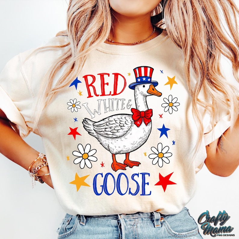 May include: A white t-shirt with a red, white, and blue goose wearing a hat with stars and stripes. The text "Red White & Goose" is printed on the shirt.