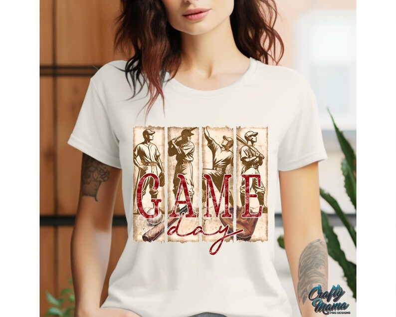 K&ouml;nnte beinhalten: Cremefarbenes T-Shirt mit Baseball-Motiv. Das Design umfasst vier Baseballspieler und die Worte "GAME DAY" in einem Used-Vintage-Stil. Die Grafik ist in Braun- und Rott&ouml;nen gehalten.