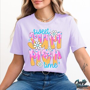 Pu&ograve; includere: Una maglietta viola con il testo "Sweet Summer Time" in un design colorato di cono gelato che cola.
