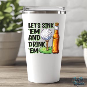 Pode incluir: Caneca t&eacute;rmica branca com um design tem&aacute;tico de golfe. O design apresenta uma bola de golfe num tee, uma garrafa de cerveja e o texto "Let's Sink 'Em and Drink 'Em". A caneca tem uma tampa prateada.
