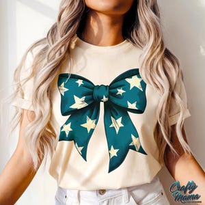 May include: A white t-shirt with a blue and white bow with stars printed on it.