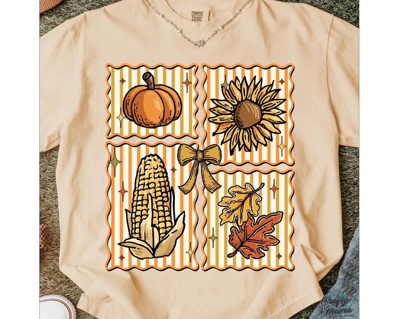 Puede incluir: Camiseta beige con un gr&aacute;fico tem&aacute;tico de oto&ntilde;o. El dise&ntilde;o incluye una calabaza, un girasol, ma&iacute;z, un lazo y hojas de oto&ntilde;o, todo dentro de marcos decorativos. La camiseta tiene una etiqueta Comfort Colors.
