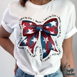 May include: White t-shirt with a red, white, and blue bow with stars. The bow is surrounded by the text "Land of the Free" and "America".