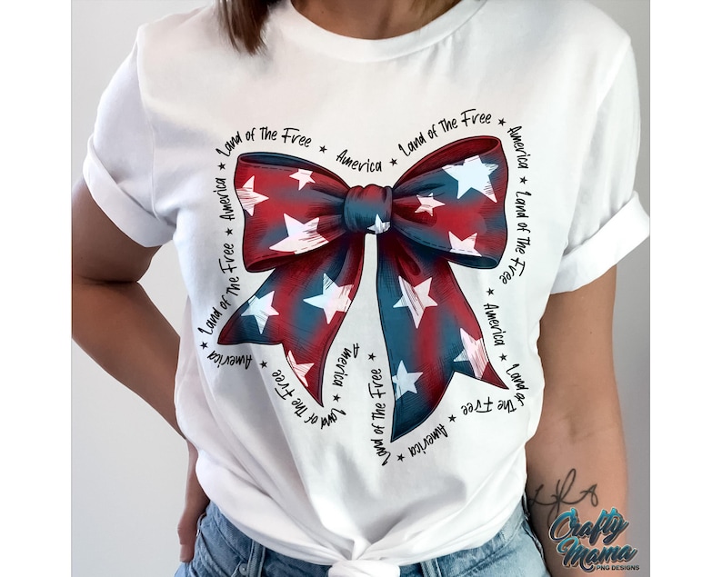May include: White t-shirt with a red, white, and blue bow with stars. The bow is surrounded by the text "Land of the Free" and "America".
