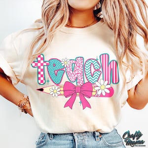 May include: A white t-shirt with the word "teach" in colorful patterned letters. The letters are decorated with a pencil, a bow, and flowers.