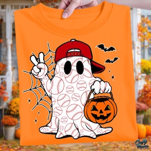 May include: Orange t-shirt featuring a baseball-themed ghost wearing a red baseball cap and holding a jack-o'-lantern. The ghost is white with baseball patterns and a peace sign. Black bats and a spiderweb complete the Halloween design.
