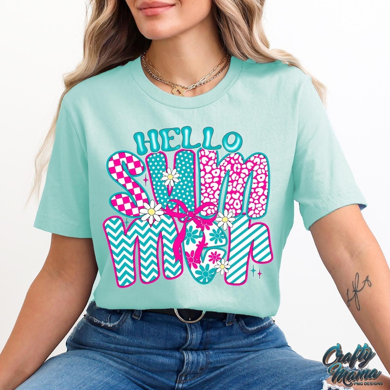 May include: A turquoise blue t-shirt with the text "Hello Summer" in pink, blue, and white patterned letters. The letters are decorated with flowers and geometric shapes.