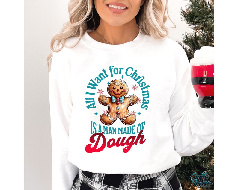 May include: White sweatshirt with a gingerbread man graphic and the text "All I want for Christmas is a man made of dough." The gingerbread man has a blue bow tie and is surrounded by blue stars.