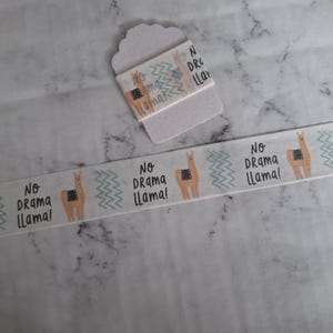 Puede incluir: Cinta washi blanca con un patrón repetido de llamas y el texto "No Drama Llama!" en negro. La cinta está sobre un fondo blanco.