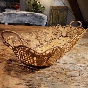 May include: A woven wicker basket with a scalloped edge and intricate design. The basket is light brown and has a rectangular shape.