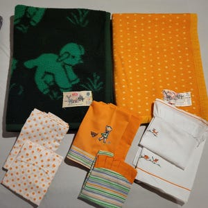 May include: A set of vintage blankets and pillowcases. The blankets are green with a white lamb design and yellow with white polka dots. The pillowcases are white with embroidered designs of a girl with a wagon and a bird.