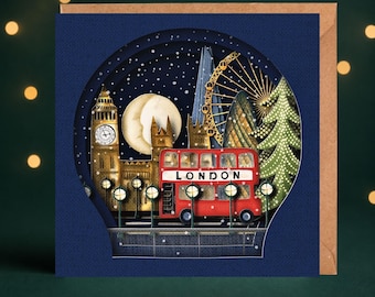 May include: A square greeting card featuring a layered paper-cut design of a snowy London night scene. The illustration includes Big Ben, the London Eye, a red double-decker bus with the word LONDON printed on its side, and a decorated pine tree.