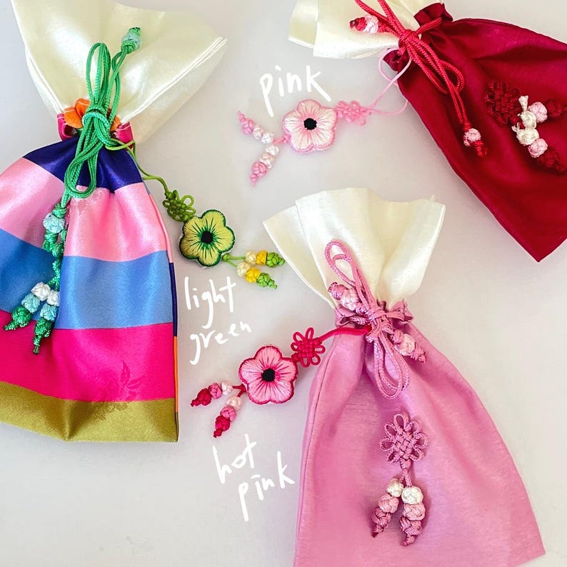Pu&ograve; includere: Quattro sacchetti di raso colorati con accenti floreali decorativi. I sacchetti sono in tonalit&agrave; di rosa, rosso e blu, con la parte superiore bianca. L'immagine include il testo "pink", "light green" e "hot pink".