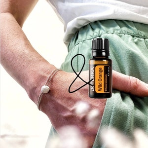 May include: A brown glass bottle with a black cap and a white label that says "doTERRA Wild Orange Citrus sinensis 15 ml".