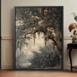May include: A framed landscape painting in muted tones of gray, brown, and beige. The artwork depicts a large tree with hanging moss, a body of water, and foliage. The painting is in a black frame.