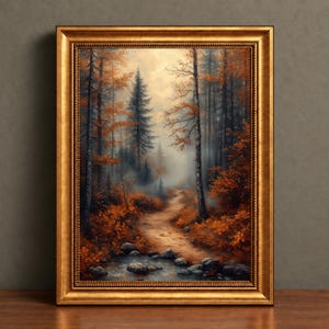 May include: A framed wall art print depicting a forest path during autumn. The scene features tall trees with orange and brown foliage, a winding dirt trail, and a small rocky stream in the foreground, all encased in a decorative gold frame.