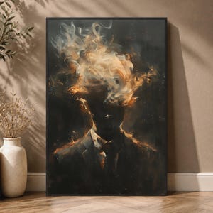 May include: A framed wall art print featuring a dark, silhouetted figure in a suit. The head area is replaced by swirling, ethereal golden and white smoke or vapor, with glowing embers and light particles scattered throughout the dark background.