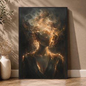 May include: A rectangular framed wall art print featuring an abstract portrait of a figure with a head composed of swirling golden smoke and light against a dark background. The figure wears a dark garment with glowing orange highlights.