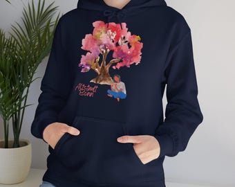 Könnte beinhalten: Ein marineblauer Hoodie mit einem rosa Aquarellbaum und einer Person, die darunter sitzt. Der Text "Altstadt Bonn" ist auf dem Hoodie aufgedruckt.