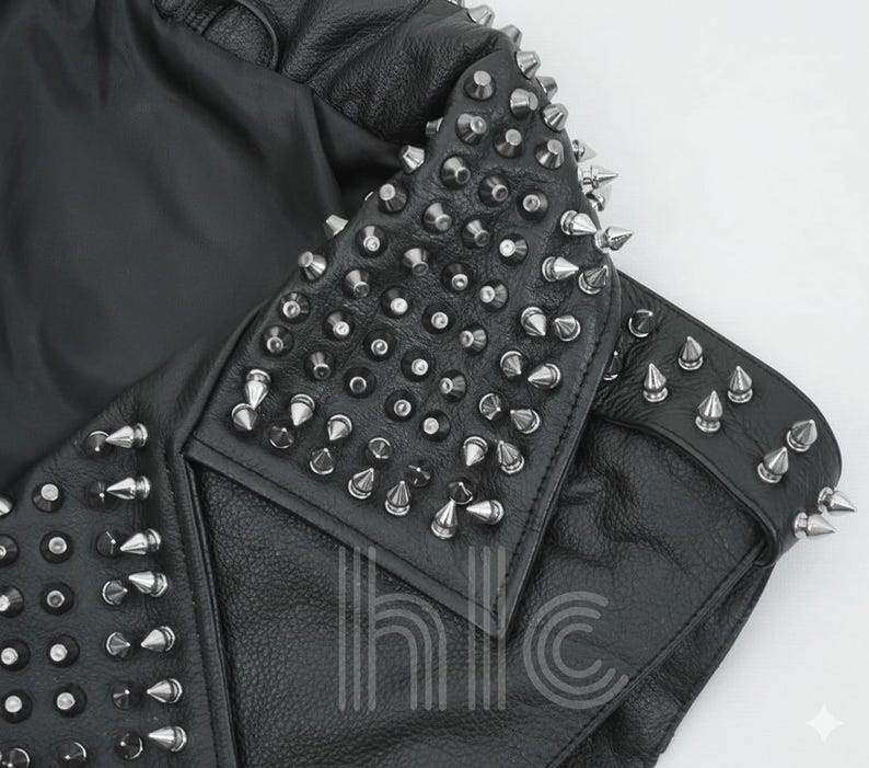 May include: Black leather jacket with silver cone studs on the collar and shoulders. The jacket has a classic biker style with a notched lapel and a fitted silhouette. The studs are evenly spaced and add a punk rock aesthetic.