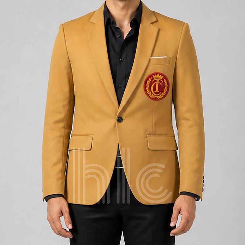 May include: Mustard yellow blazer with a black button closure, a small pocket, and a red and gold emblem on the chest. The blazer is worn over a black shirt and paired with black pants. The blazer has a classic, tailored design.