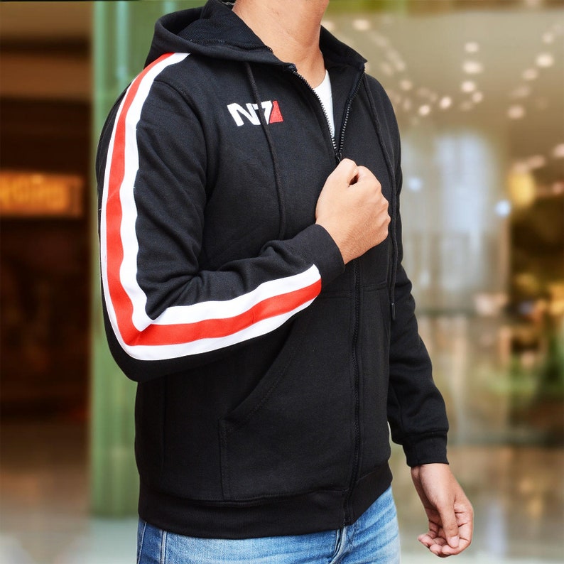 May include: Black zip-up hoodie with white and red stripes on the sleeves. The hoodie features the text "N7" in white with a red accent. The hoodie has a hood and two front pockets.