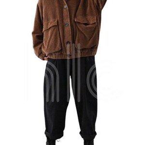 Puede incluir: Chaqueta de pana marr&oacute;n con grandes bolsillos delanteros y botones. La chaqueta se combina con pantalones negros y botas negras. El conjunto incluye una camiseta de cuello alto a rayas.