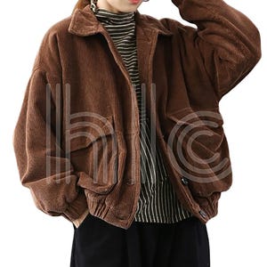 Puede incluir: Chaqueta de pana marr&oacute;n con cuello y dos bolsillos delanteros grandes. La chaqueta tiene un corte relajado y est&aacute; abotonada. La modelo lleva un cuello alto a rayas debajo. La chaqueta es de un color c&aacute;lido y neutro.