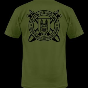 May include: A green t-shirt with a black graphic of a German Shepherd dog in a circle with the text "Explosive Detection Canine" and "Precision Unleashed: Zero Tolerance for Error".