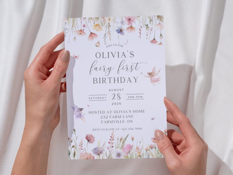 May include: A light-colored invitation with floral and fairy illustrations, held by hands. The text reads "Olivia's fairy first birthday" with the date August 28, 2025, and the time 3 PM-5 PM. The invitation includes an address and RSVP information.