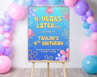 May include: A rectangular birthday sign on a wooden easel surrounded by pink, purple, and blue balloons. The blue sign features jellyfish and flower graphics with the text: 8 YEARS LATER... WELCOME TO TAYLOR'S 8TH BIRTHDAY SATURDAY APRIL 23RD, 2027 4:00PM - 6:00PM.