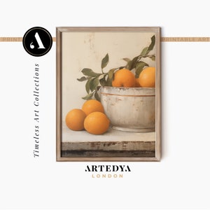 May include: A framed painting of a still life with a white bowl filled with oranges and a sprig of green leaves. The oranges are on a wooden table.