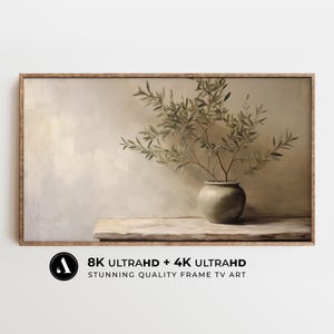 Puede incluir: Impresión enmarcada que presenta un bodegón de un jarrón con ramas de olivo. El jarrón es de color verde apagado y está sobre una superficie similar a la piedra. El fondo es de un tono suave y neutro. El marco es de color marrón claro. El texto en la imagen dice "8K ULTRAHD + 4K ULTRAHD STUNNING QUALITY FRAME TV ART."