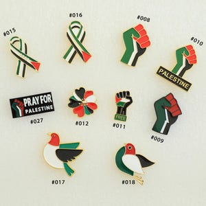 May include: A collection of enamel pins with Palestinian flag and solidarity themes. Designs include ribbon, fist, flower, and bird motifs, along with text that reads "PRAY FOR PALESTINE" and "PALESTINE". The pins feature red, green, black, and white colors.
