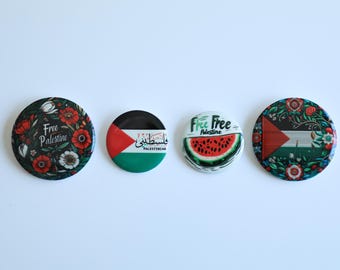 May include: Four round buttons with different designs. The first button has a black background with red and white flowers and the text "Free Palestine". The second button has a black, red, green, and white Palestinian flag with the text "Palestinian" in English and Arabic. The third button has a white background with a watermelon slice and the text "Free Free Palestine". The fourth button has a white background with a Palestinian flag and red, white, and green flowers.