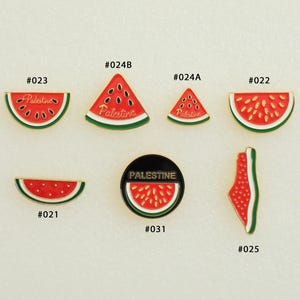 May include: A collection of watermelon-themed enamel pins. The pins feature red and green watermelon slices, triangles, and a round pin with the word "Palestine". Some pins have the word "Palestine" written on them.