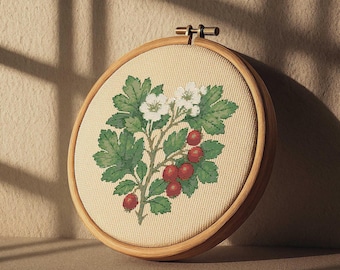 May include: A circular embroidery hoop displaying a botanical design. The design includes green leaves, white flowers, and red berries. The embroidery is set on a beige fabric and framed by a wooden hoop.