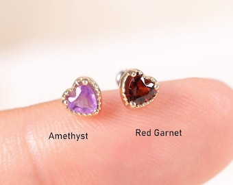 May include: Two heart-shaped stud earrings with metallic borders. One earring features a purple amethyst stone, and the other features a dark red garnet stone. The text Amethyst and Red Garnet is printed below each respective earring.
