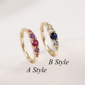 May include: Two gold hoop earrings featuring small gemstones. A Style displays pink and purple stones, while B Style features a central dark blue stone flanked by lighter blue and clear stones. The text A Style and B Style is printed below.
