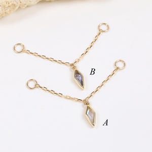 May include: Two gold-toned jewelry connectors, labeled A and B, each featuring two thin chains attached to a central diamond-shaped pendant with a light-colored stone. Each chain ends in a small circular jump ring for attachment purposes.
