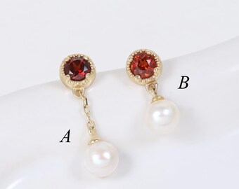 May include: Two gold earrings labeled A and B. Earring A features a round red gemstone in a scalloped setting connected by a short chain to a white pearl. Earring B features a round red gemstone in a scalloped setting with a white pearl attached.