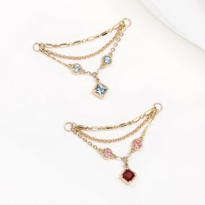 May include: Two gold-toned jewelry connectors featuring multi-strand chains with small metallic beads. One connector displays light blue circular stones and a square blue pendant, while the other features pink circular stones and a square red pendant.