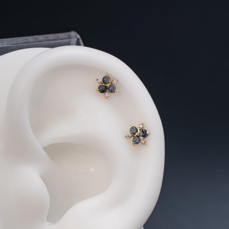 Puede incluir: Un par de pendientes de oro con un grupo de piedras preciosas azules y peque&ntilde;os diamantes en forma de flor.
