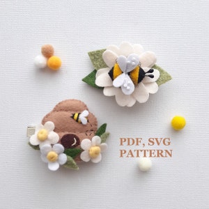 May include: Two felt bee and flower hair clips. One clip features a brown felt beehive with white flowers and a yellow bee. The other clip features a white felt flower with a yellow and black bee. The text "PDF, SVG PATTERN" is printed on a white background.