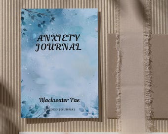Può includere: Una copertina di diario in acquerello blu e bianca con il testo "Anxiety Journal" e "Blackwater Fae Guided Journal".