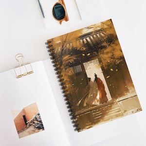 Può includere: Quaderno a spirale con un'illustrazione di due figure in abiti tradizionali che attraversano una porta. L'opera d'arte ha una calda tavolozza di colori con sfumature di oro, marrone e arancione. Il quaderno è aperto su una superficie bianca.