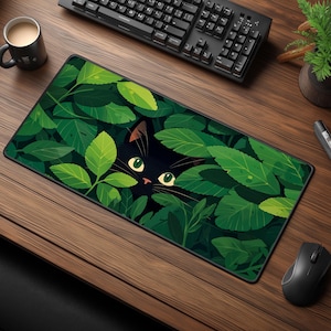May include: A rectangular mouse mat with a design of a black cat amongst green leaves. The cat has yellow eyes and brown ears. The mat sits on a wooden desk with a keyboard, mouse, and a coffee mug.